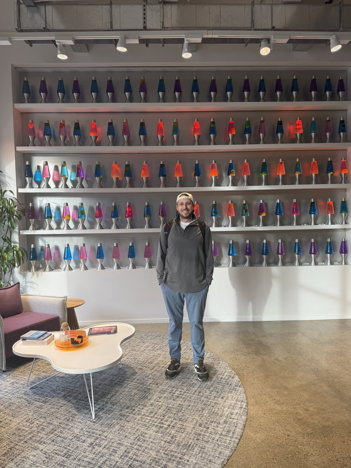 Jordan standing in front of five shelves of lava lamps in Cloudflare's San Francisco lobby